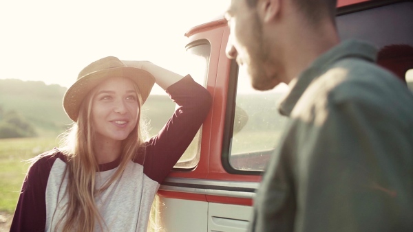 A young couple on a roadtrip through countryside, talking. Slow motion.