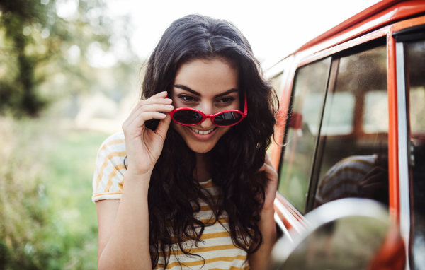 A girl with sunglasses looking in mirror on a roadtrip through countryside.