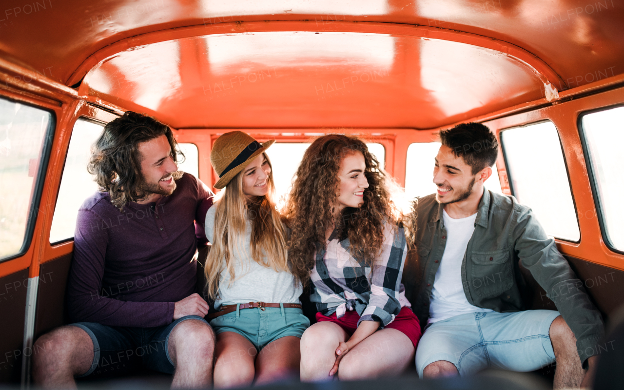 A group of young friends on a roadtrip through countryside, sitting in a retro minivan.