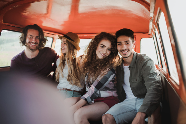 A group of young friends on a roadtrip through countryside, sitting in a retro minivan.