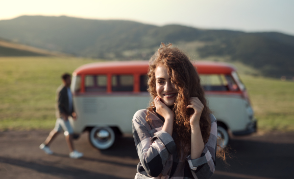 A young girl on a roadtrip through countryside, standing by a minivan. Copy space.