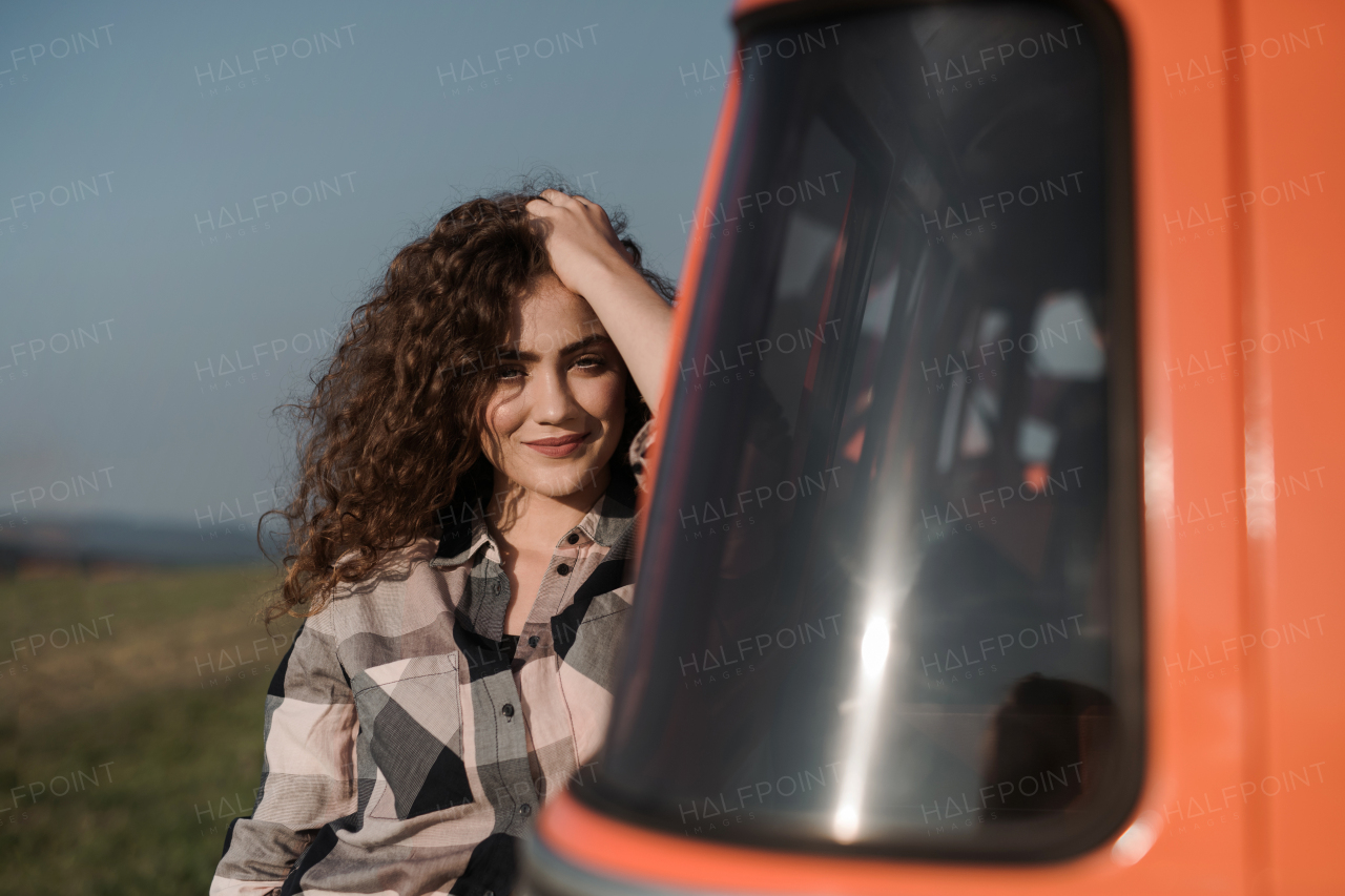 A young girl on a roadtrip through countryside, standing by a minivan. Copy space.