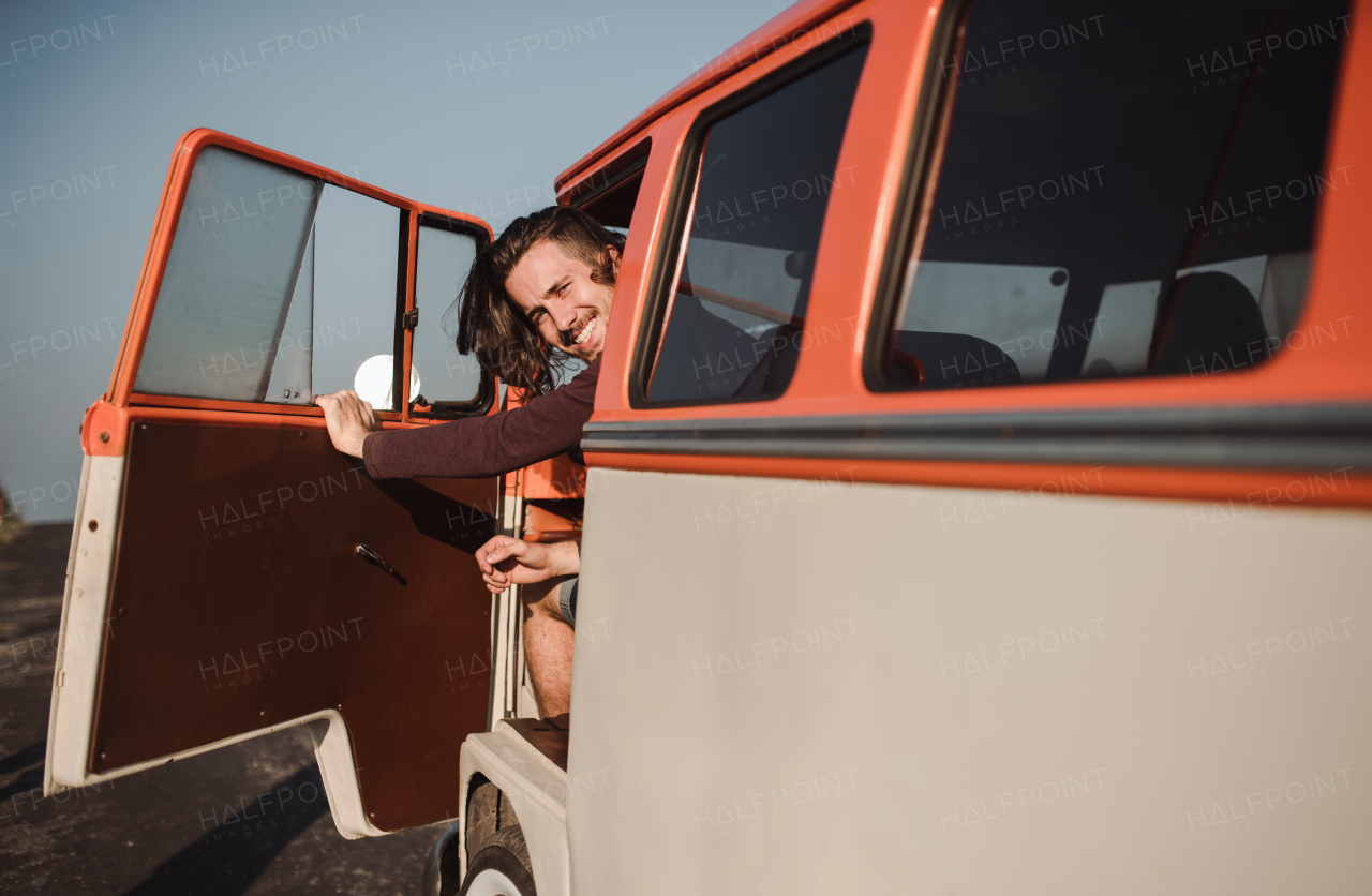 A cheerful young man getting out of a car on a roadtrip through countryside. Copy space.