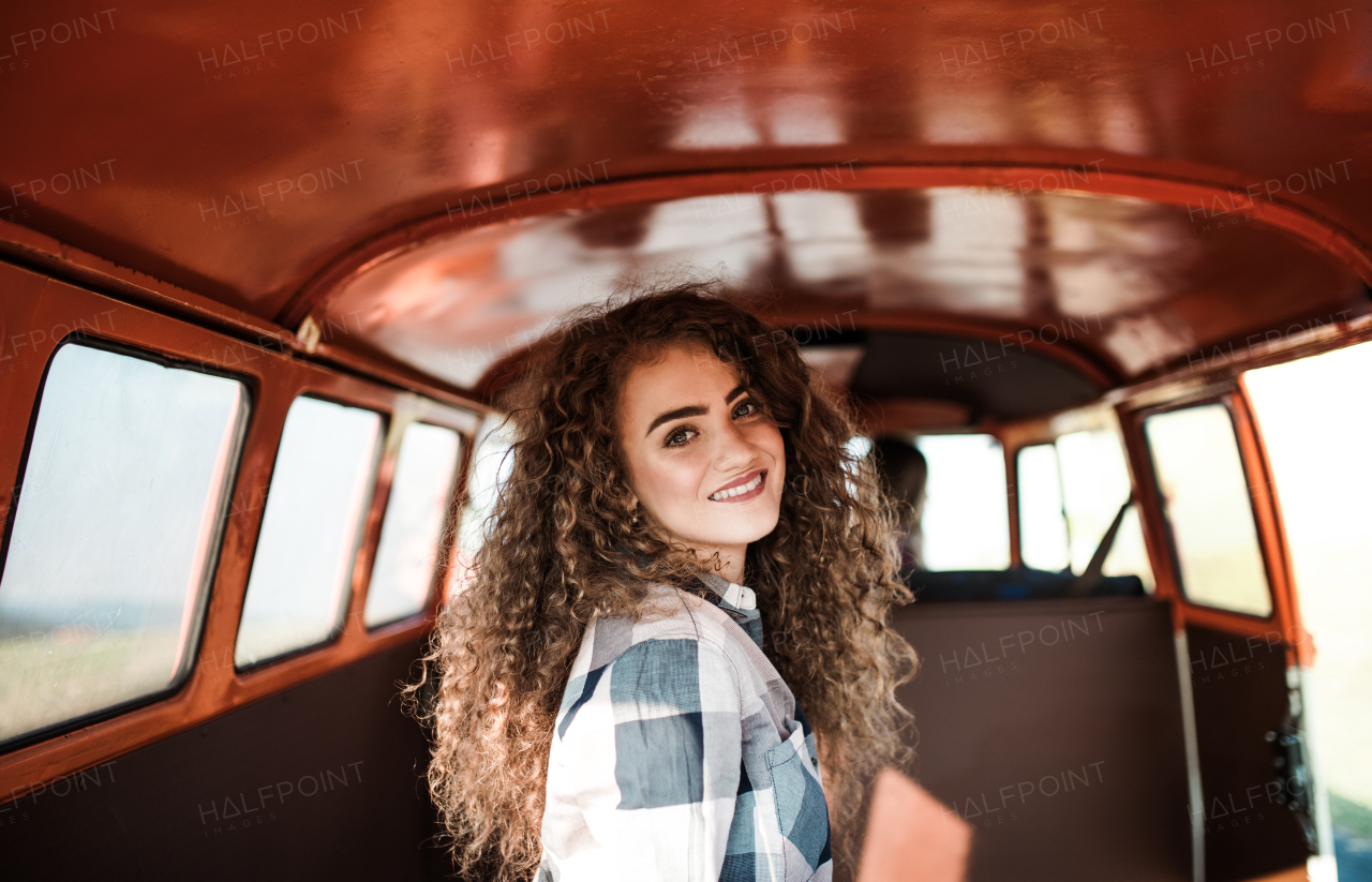 A cheerful young girl in a car on a roadtrip through countryside.