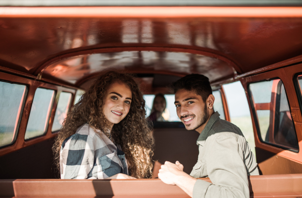 A group of young friends on a roadtrip through countryside, sitting in a retro minivan.