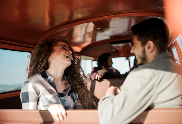 A group of young friends on a roadtrip through countryside, sitting in a retro minivan.