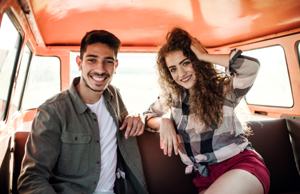 A young couple on a roadtrip through countryside, driving retro minivan.