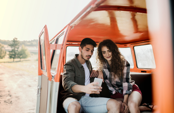 A young couple on a roadtrip through countryside, taking selfie.