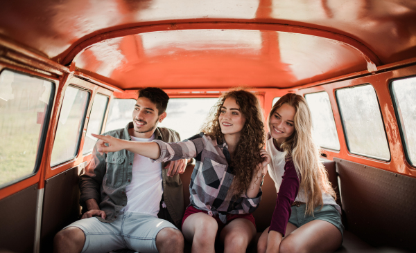 A group of young friends on a roadtrip through countryside, sitting in a retro minivan.