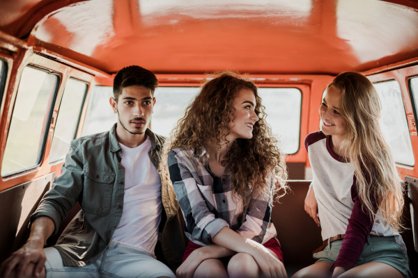 A group of young friends on a roadtrip through countryside, sitting in a retro minivan.