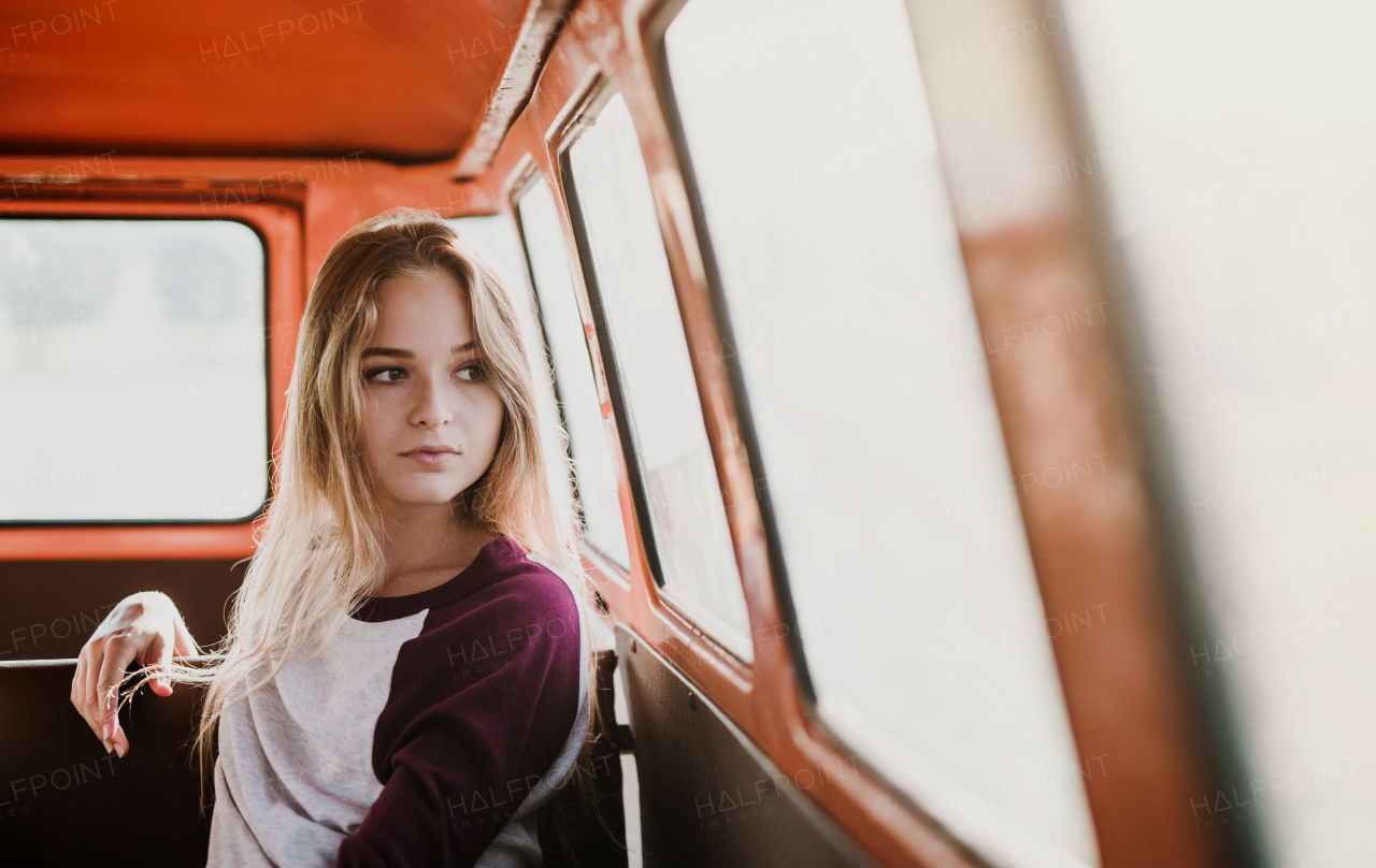 A cheerful young girl sitting a car on a roadtrip through countryside.