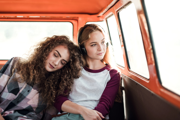 Young female friends on a roadtrip through countryside, sitting in a minivan.