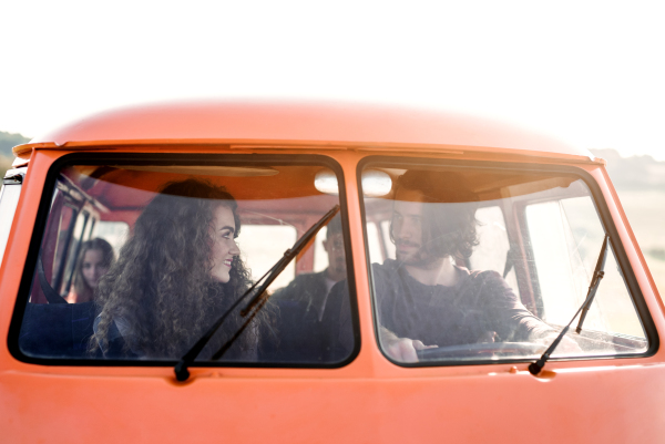 A group of young friends on a roadtrip through countryside, sitting in a retro minivan.