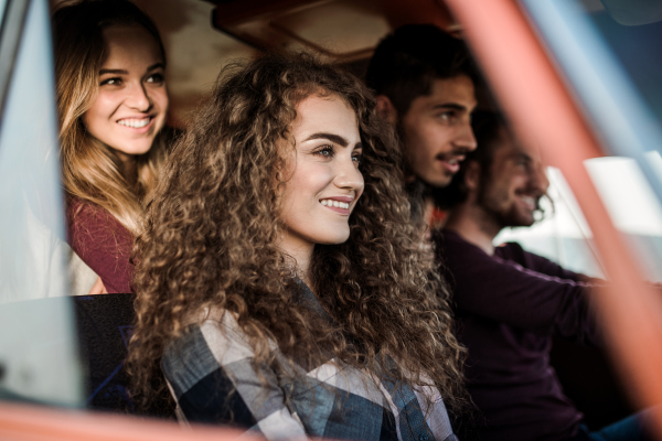 A group of young friends on a roadtrip through countryside, sitting in a retro minivan.