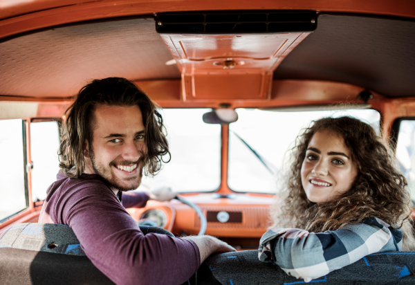 A young couple on a roadtrip through countryside, driving retro minivan.