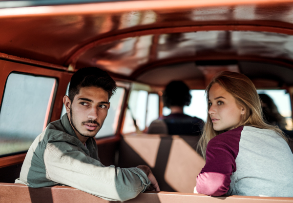 A group of young friends on a roadtrip through countryside, sitting in a retro minivan.