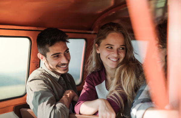 A group of young friends on a roadtrip through countryside, sitting in a retro minivan.