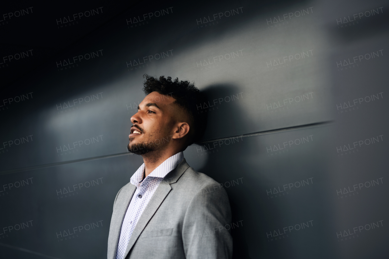 A portrait of young man student standing outdoors in city against black background.