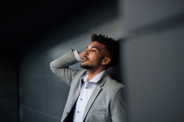 A portrait of young man student standing outdoors in city against black background.