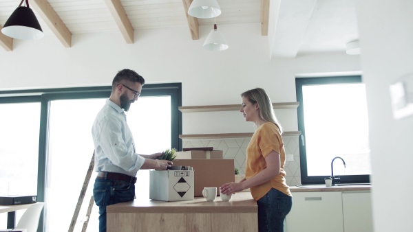 A young happy couple furnishing new house, unpacking stuff. A moving in new home concept.