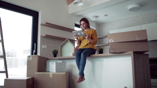 A young happy woman with tablet planning when moving in new home.