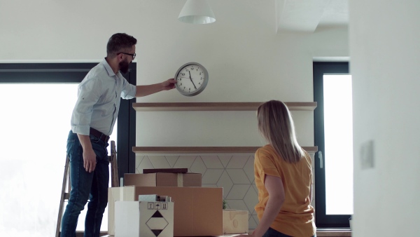 A young happy couple furnishing new house, talking. A moving in new home concept.