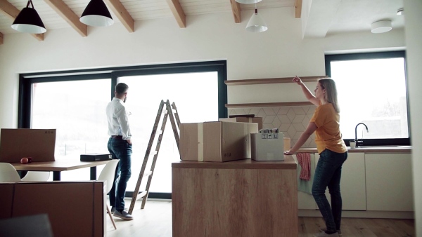 A young happy couple furnishing new house, talking. A moving in new home concept. Slow motion.