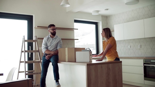 A young happy couple furnishing new house, talking. A moving in new home concept. Slow motion.