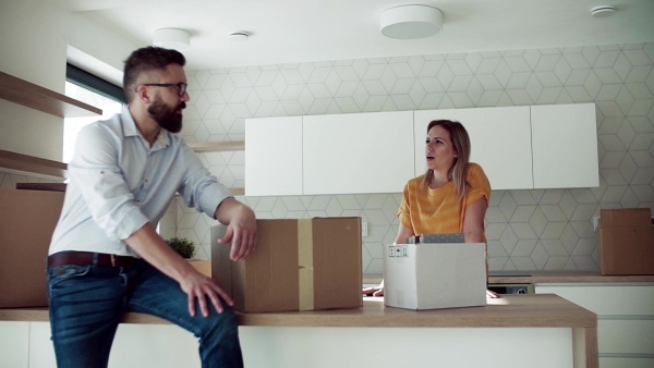 A young happy couple furnishing new house, talking. A moving in new home concept. Slow motion.