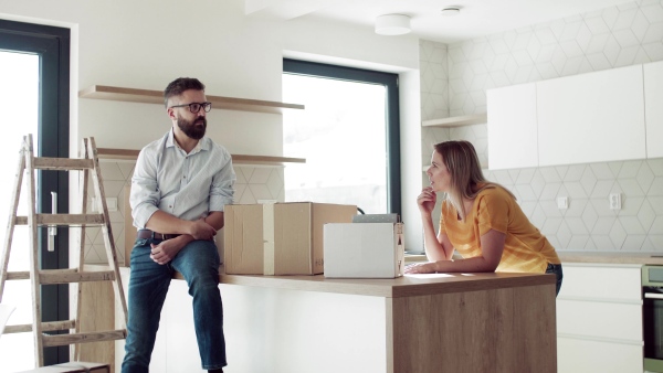 A young happy couple furnishing new house, talking. A moving in new home concept.