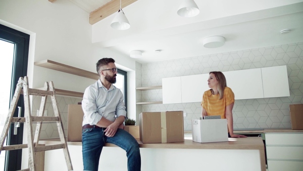 A young happy couple furnishing new house, talking. A moving in new home concept. Slow motion.