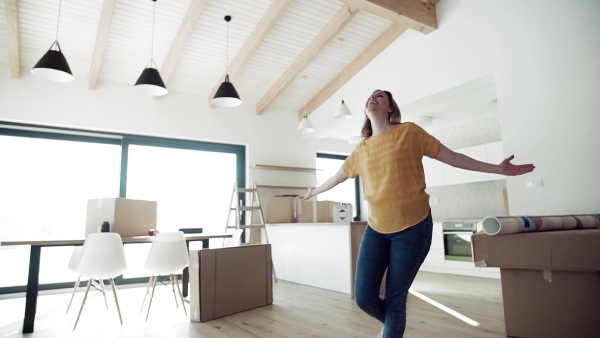 A joyful young woman moving in new home, spinning and expressing excitement. Slow motion.