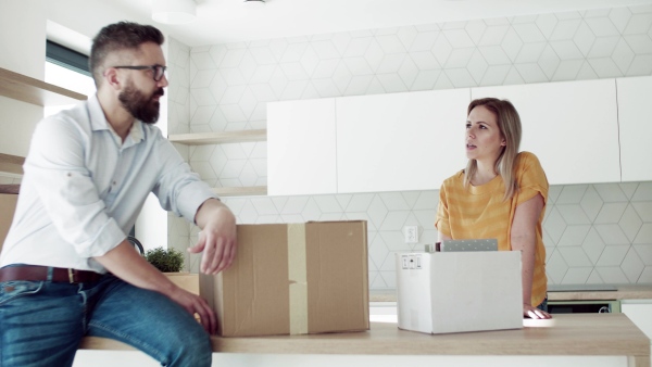 A young happy couple furnishing new house, talking. A moving in new home concept.