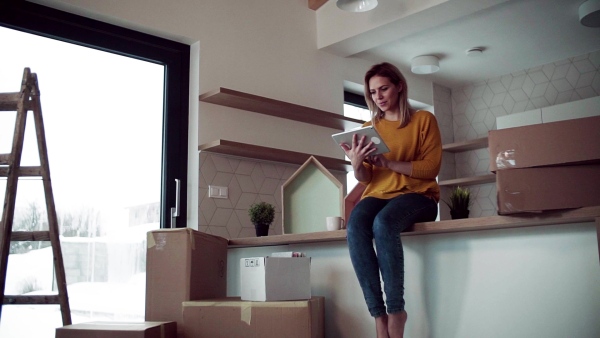 A young happy woman with tablet planning when moving in new home. Slow motion.