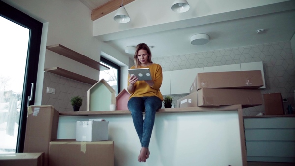 A young happy woman with tablet planning when moving in new home. Slow motion.