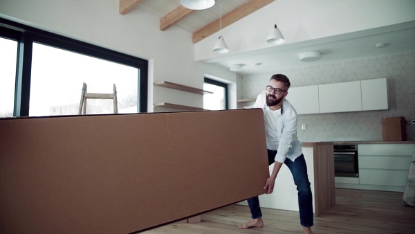 A young happy couple furnishing new house, carrying a large box. A moving in new home concept. Slow motion.