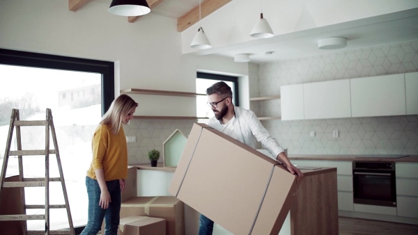 A young happy couple furnishing new house, unpacking stuff. A moving in new home concept. Slow motion.