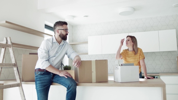 A young happy couple furnishing new house, talking. A moving in new home concept.