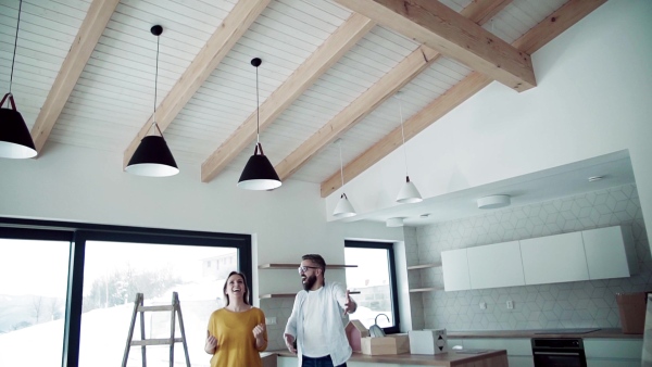 A joyful young happy couple furnishing new house, expressing excitement. A moving in new home concept. Slow motion.