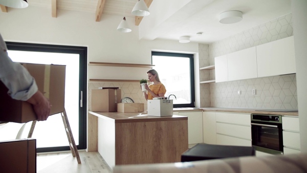 A young happy couple furnishing new house, unpacking stuff. A moving in new home concept. Slow motion.