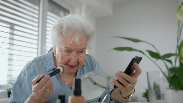 A senior woman doing her make up routine in front of the mirror.