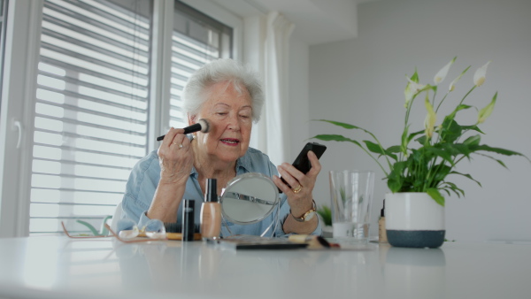 A senior woman doing her make up routine in front of the mirror.