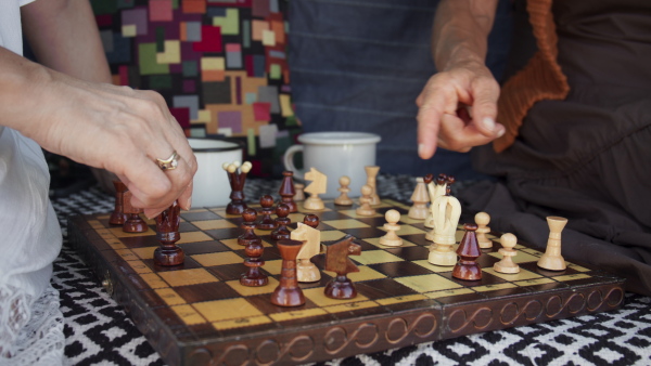 Senior women friends resting and drinking tea while playing a chess, caravan trip holiday.