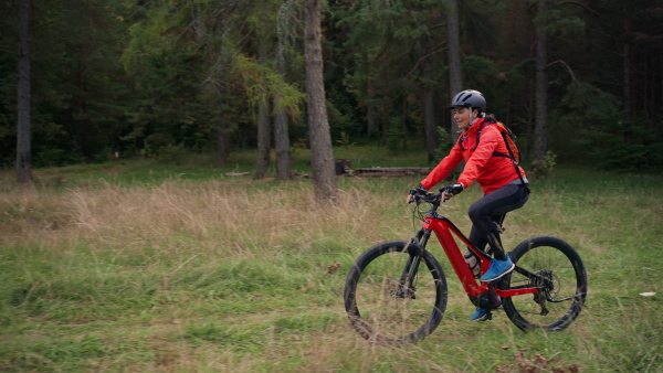 An active senior woman biker riding bike in nature on autumn day.