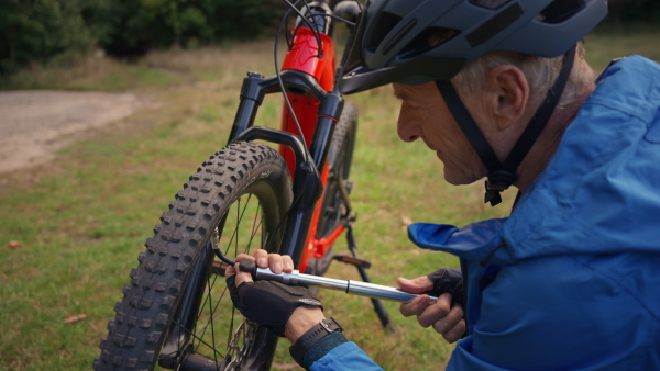 A close-up of a man pumping bicycle wheel in nature.