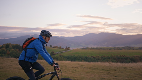 An active senior man biker riding bike in nature on autumn day.