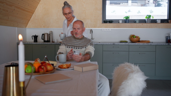 A senior couple spenidng time together in morning in kitchen.