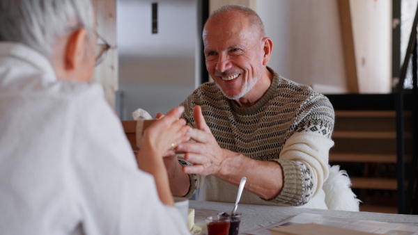 A senior woman getting present from her husband at home during breakfast.