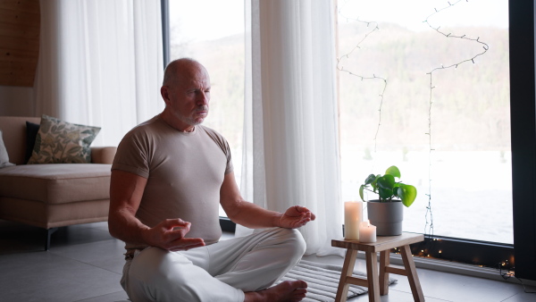 A senior man meditating at home.