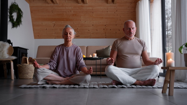 A senior couple meditating together at home.